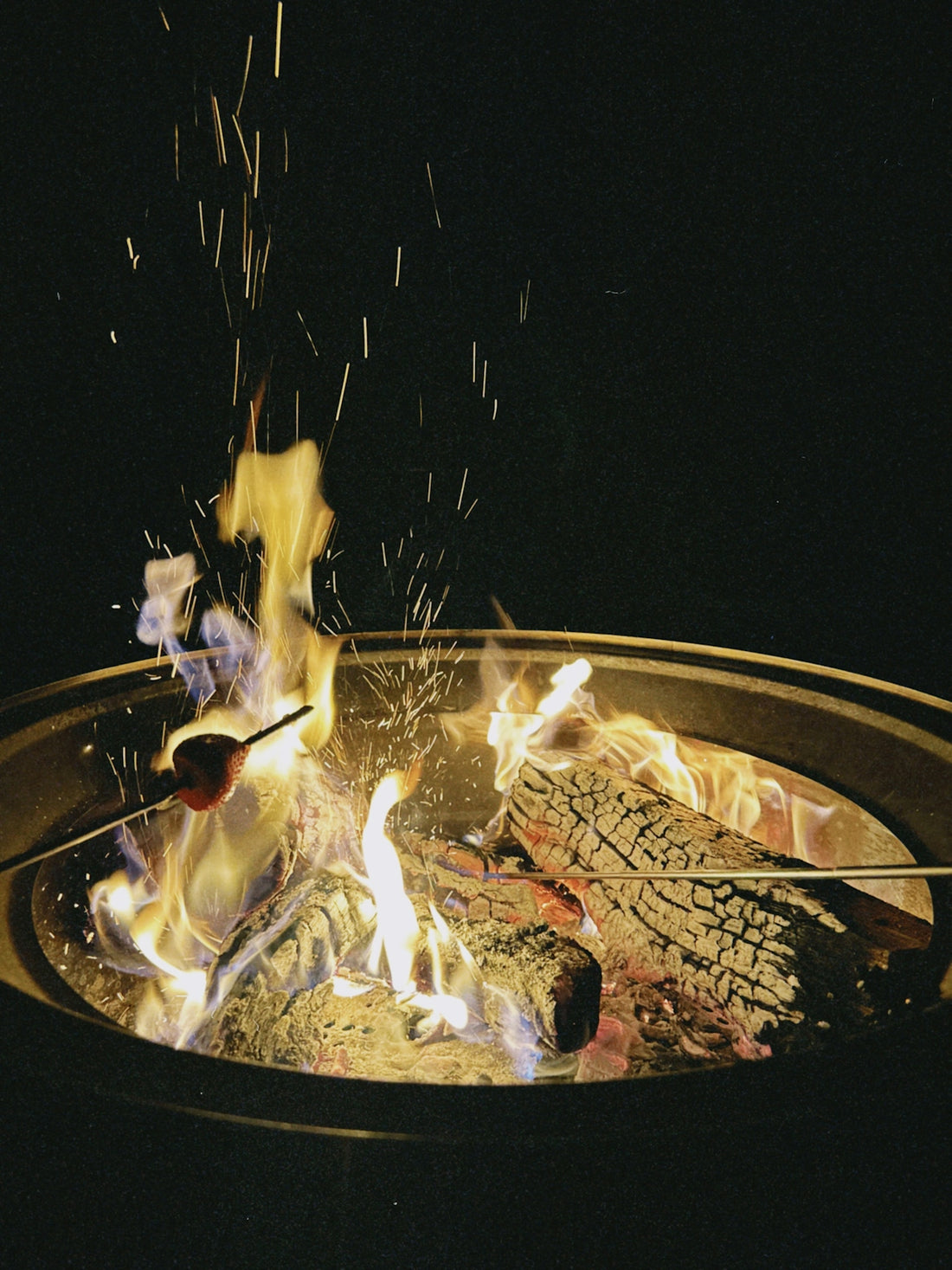 Roasting marshmallows over a glowing campfire at night