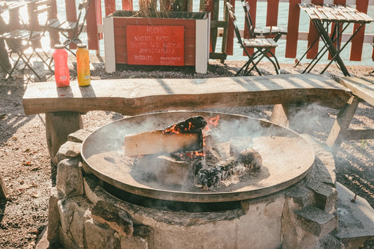 Fire pit with burning logs and smoke outdoors.