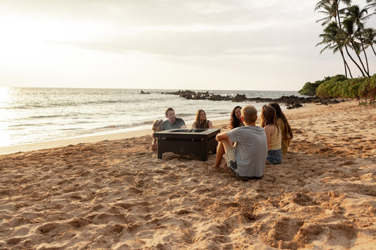 Friends gathered around a fire pit on a beach.